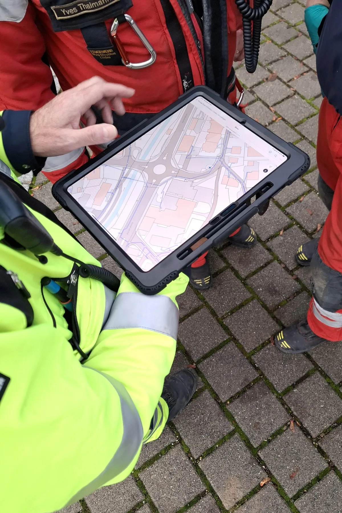 Digitale Karten helfen den Einsatzkräften zur besseren Übersicht. Ein Feuerwehrmann hält ein Tablet mit einer Karte in der Hand.
